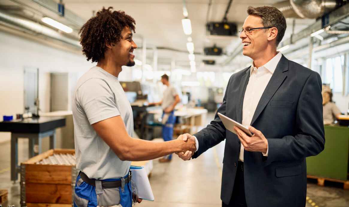 Happy manager and African American steel worker shaking hands in