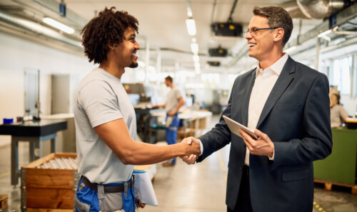 Happy manager and African American steel worker shaking hands in